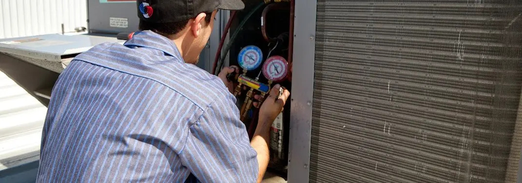 HVAC technician servicing a condenser unit in Bartlett